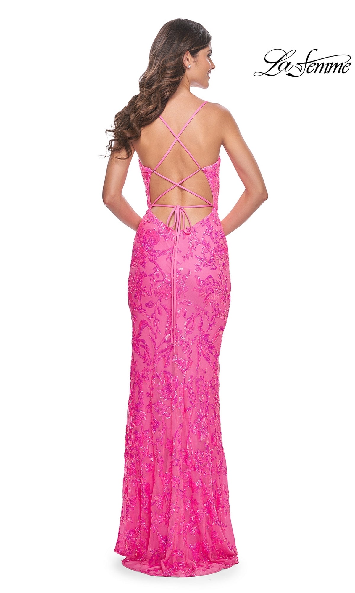 A woman stands facing away in the La Femme Neon Pink Long Sequin Prom Dress 32332, a fitted, floor-length gown with strappy open back. The La Femme logo appears in the upper right corner.